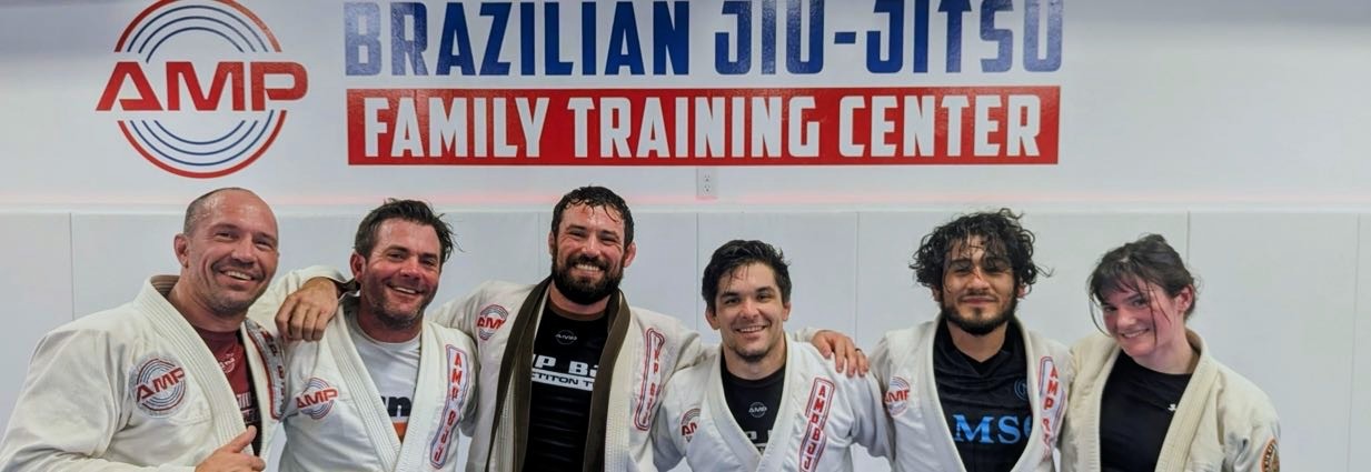 AMP BJJ coaching team lined up together under the gym banner
