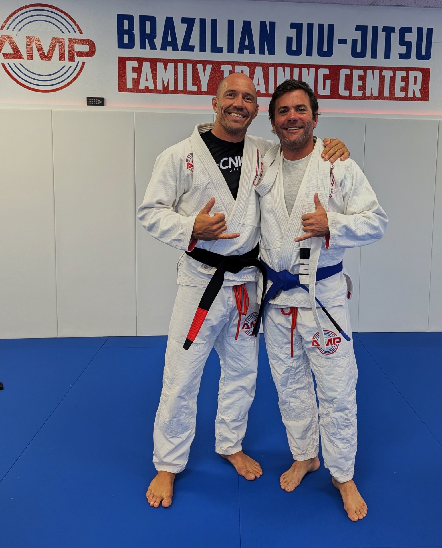 AMP BJJ black belt head coach standing with a student