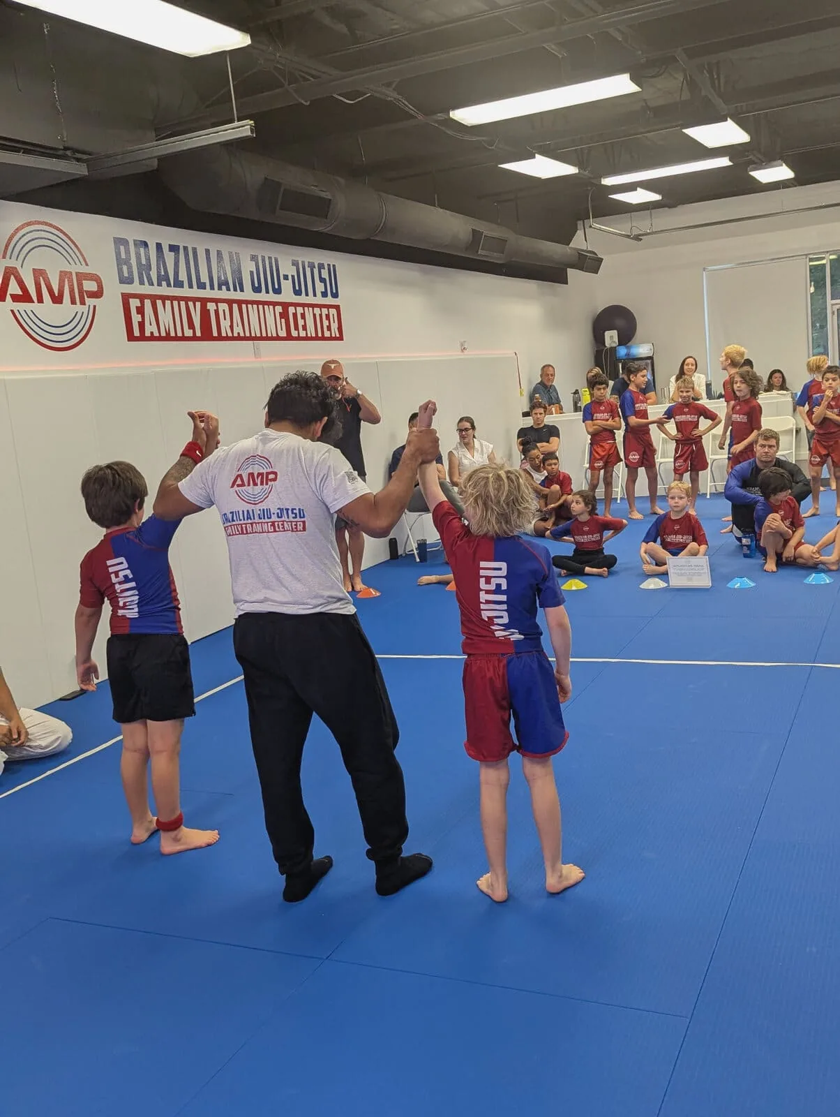 AMP BJJ coach raising a young competitor's hand in victory after an in-house tournament match in Austin, TX