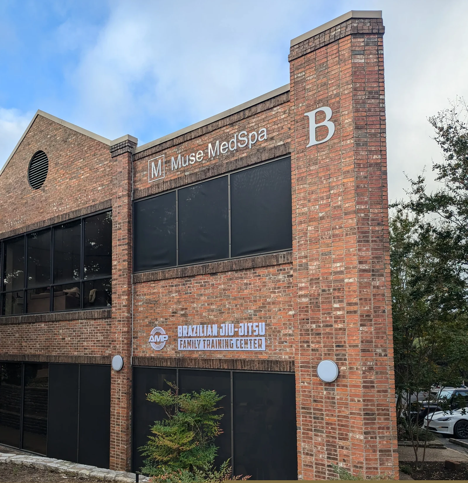 AMP BJJ Westlake Hills storefront — Brazilian Jiu-Jitsu Family Training Center on Bee Caves Rd, red brick building with AMP logo